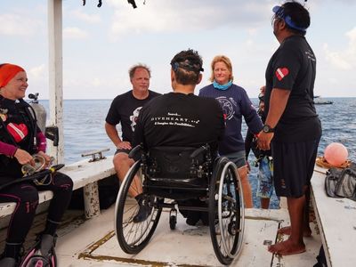 Adaptive scuba Diver in wheelchair on boat with volunteer scuba divers