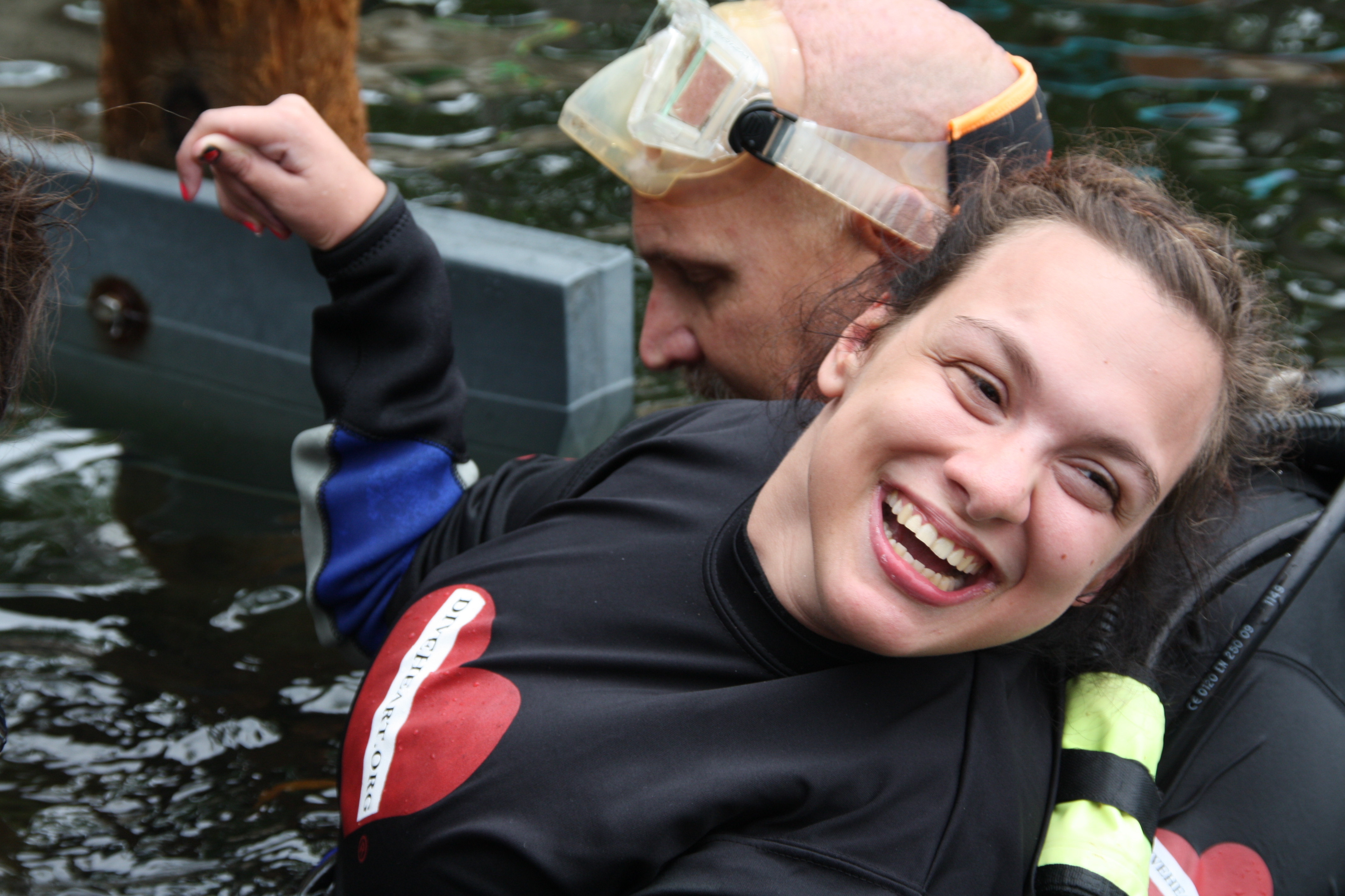 smiling adaptive scuba diver in water with dive buddy