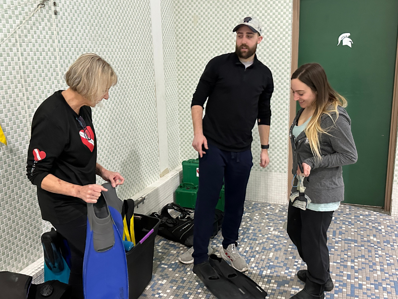 volunteer fitting adaptive diver for scuba equipment